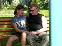 Sitting on the bench with her lover the kinky girl Ellina notices our cameraman and stretches legs wider showing naked up skirt!